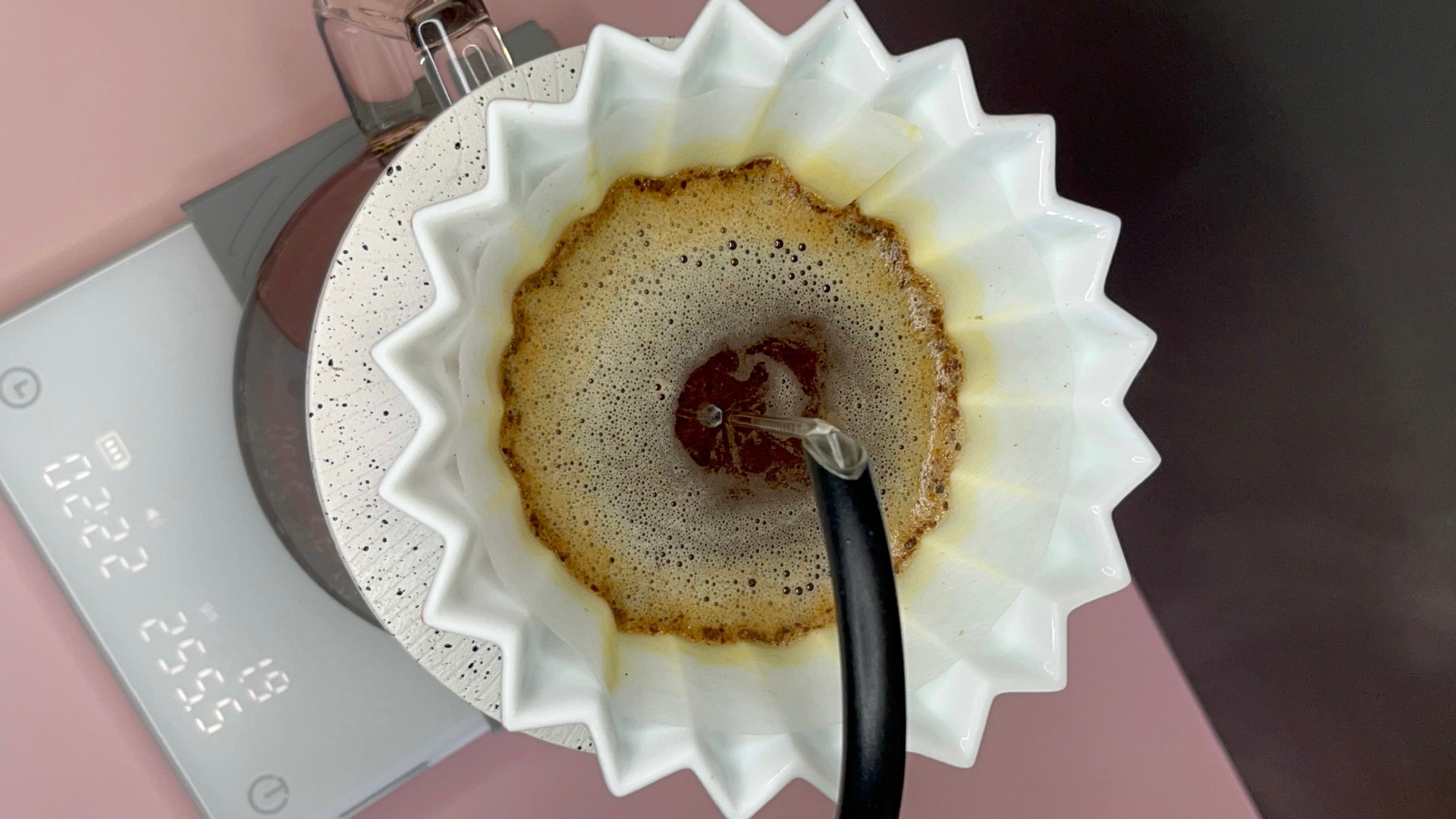 Coffee being brewed into a white filter with a digital scale in the background