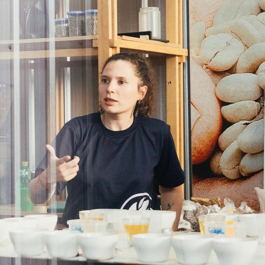 Person in a black shirt sitting at a table with bowls, gesturing with their hands.